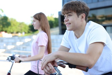 Photo of Teenage girl and boy riding bicycles on city street, selective focus
