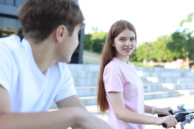 Photo of Teenage girl and boy riding bicycles on city street