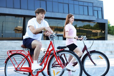 Photo of Teenage girl and boy riding bicycles on city street
