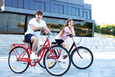 Photo of Teenage girl and boy riding bicycles on city street