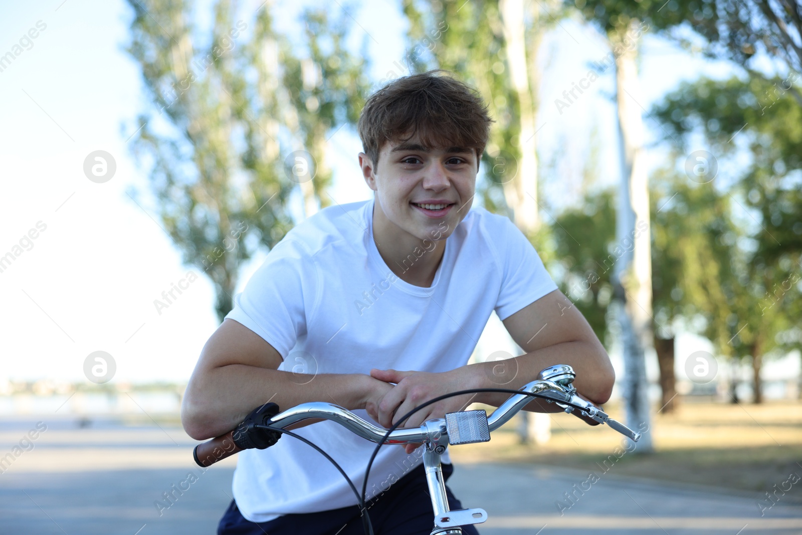 Teenage boy riding bicycle on city street Photo of Teenage boy riding bicycle on city street