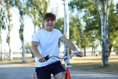 Photo of Teenage boy riding bicycle on city street, space for text