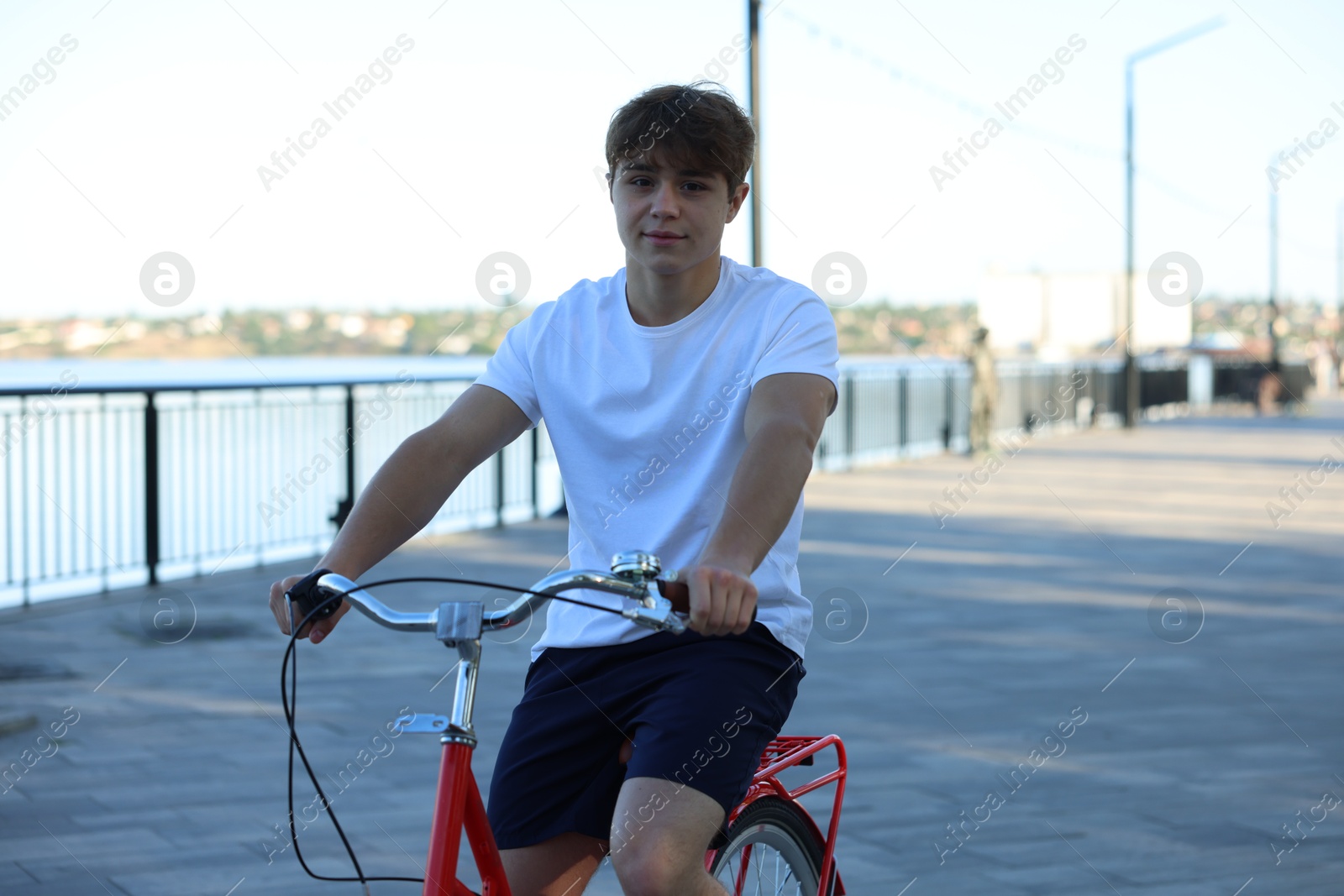 Teenage boy riding bicycle on city street, space for text Photo of Teenage boy riding bicycle on city street, space for text