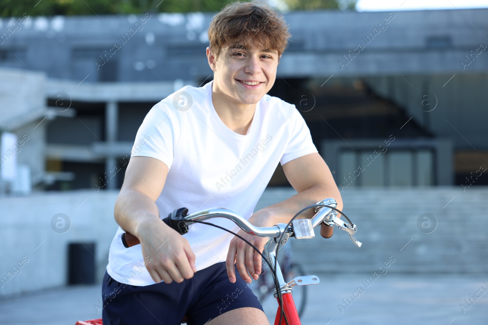 Teenage boy riding bicycle on city street Photo of Teenage boy riding bicycle on city street