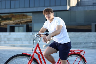 Photo of Teenage boy riding bicycle on city street