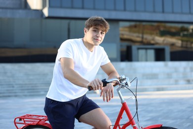 Photo of Teenage boy riding bicycle on city street