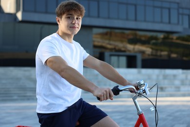 Photo of Teenage boy riding bicycle on city street