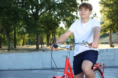Photo of Teenage boy riding bicycle on city street, space for text