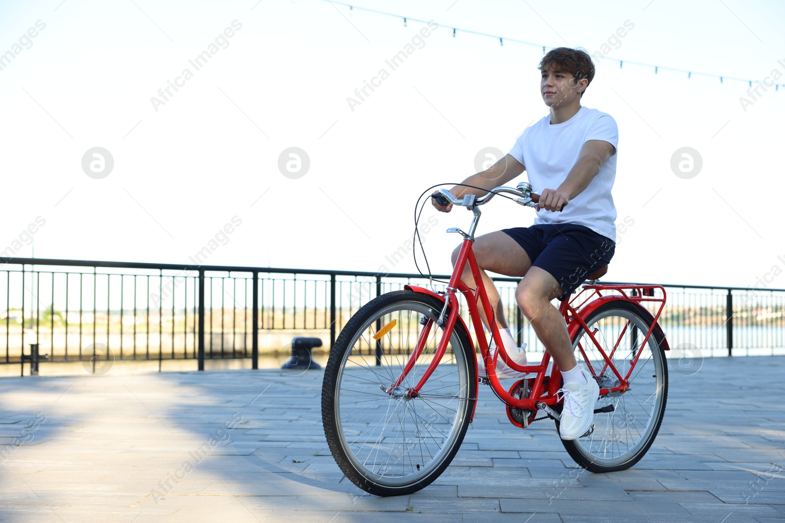 Teenage boy riding bicycle on city street, space for text Photo of Teenage boy riding bicycle on city street, space for text