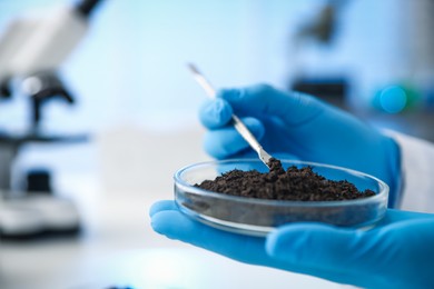 Photo of Scientist taking soil sample for research at white table in laboratory, closeup