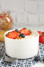 Photo of Tasty yogurt with granola, berries and honey on table, closeup