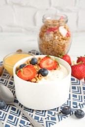 Photo of Tasty yogurt with granola, berries and honey on table, closeup