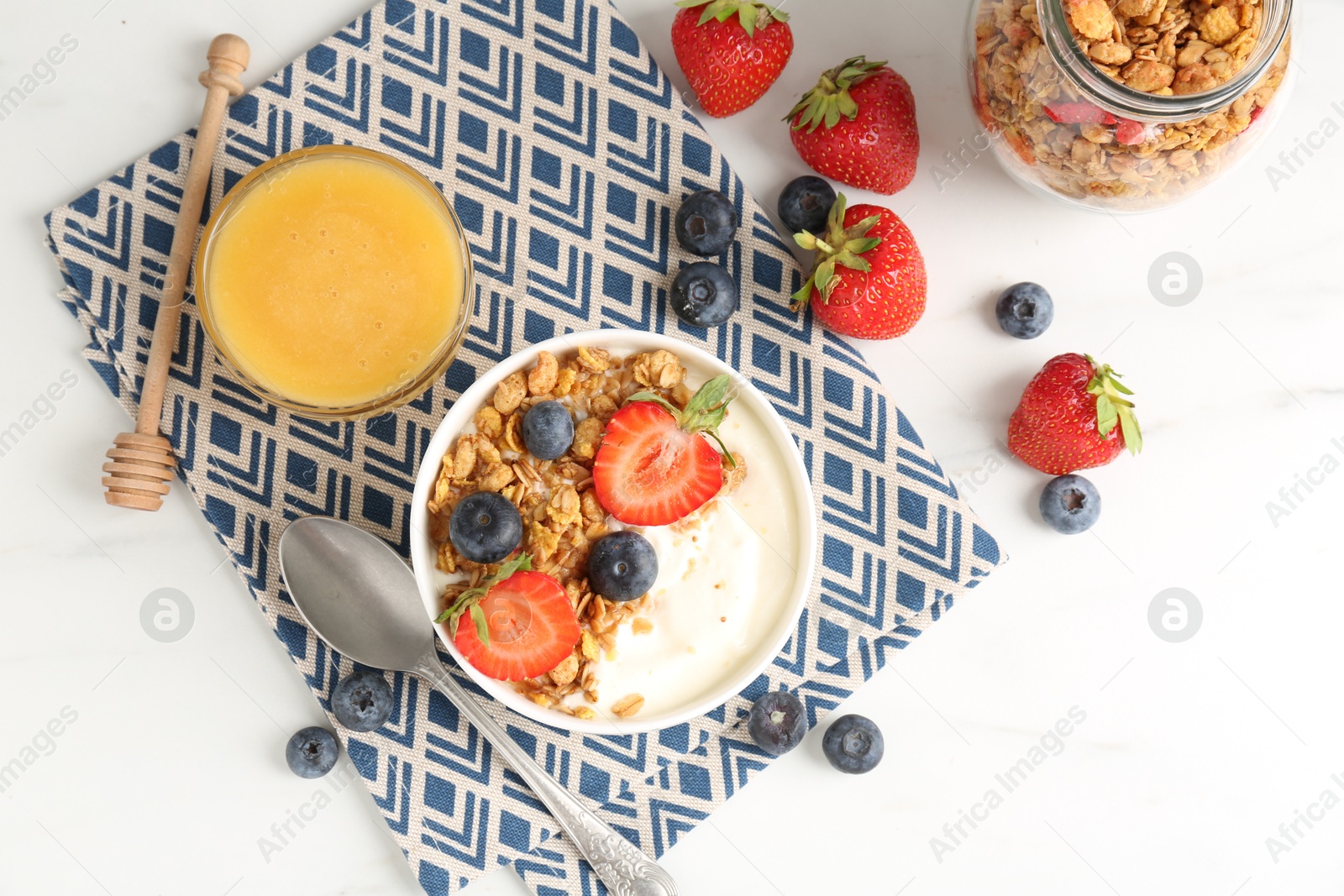Tasty yogurt with granola, berries and honey on white marble table, flat lay Photo of Tasty yogurt with granola, berries and honey on white marble table, flat lay