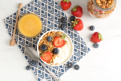 Photo of Tasty yogurt with granola, berries and honey on white marble table, flat lay