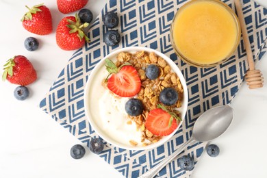 Photo of Tasty yogurt with granola, berries and honey on white marble table, flat lay