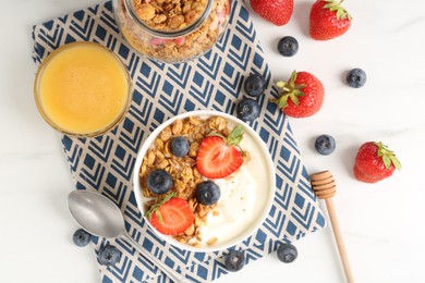 Photo of Tasty yogurt with granola, berries and honey on white marble table, flat lay