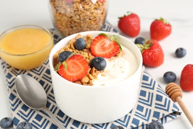 Photo of Tasty yogurt with granola, berries and honey on table, closeup