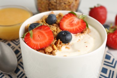 Photo of Tasty yogurt with granola, berries and honey on table, closeup