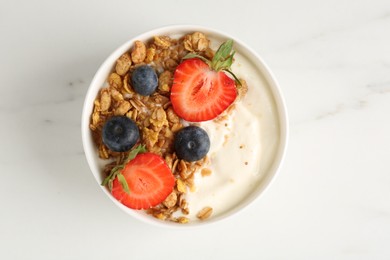 Photo of Tasty yogurt with granola and berries on white marble table, top view
