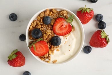 Photo of Tasty yogurt with granola and berries on white marble table, flat lay