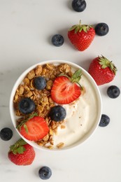 Photo of Tasty yogurt with granola and berries on white marble table, flat lay