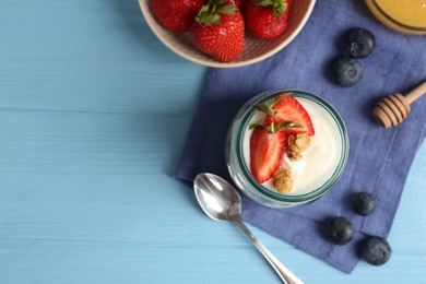 Photo of Tasty yogurt with granola, berries and spoon on light blue wooden table, flat lay. Space for text