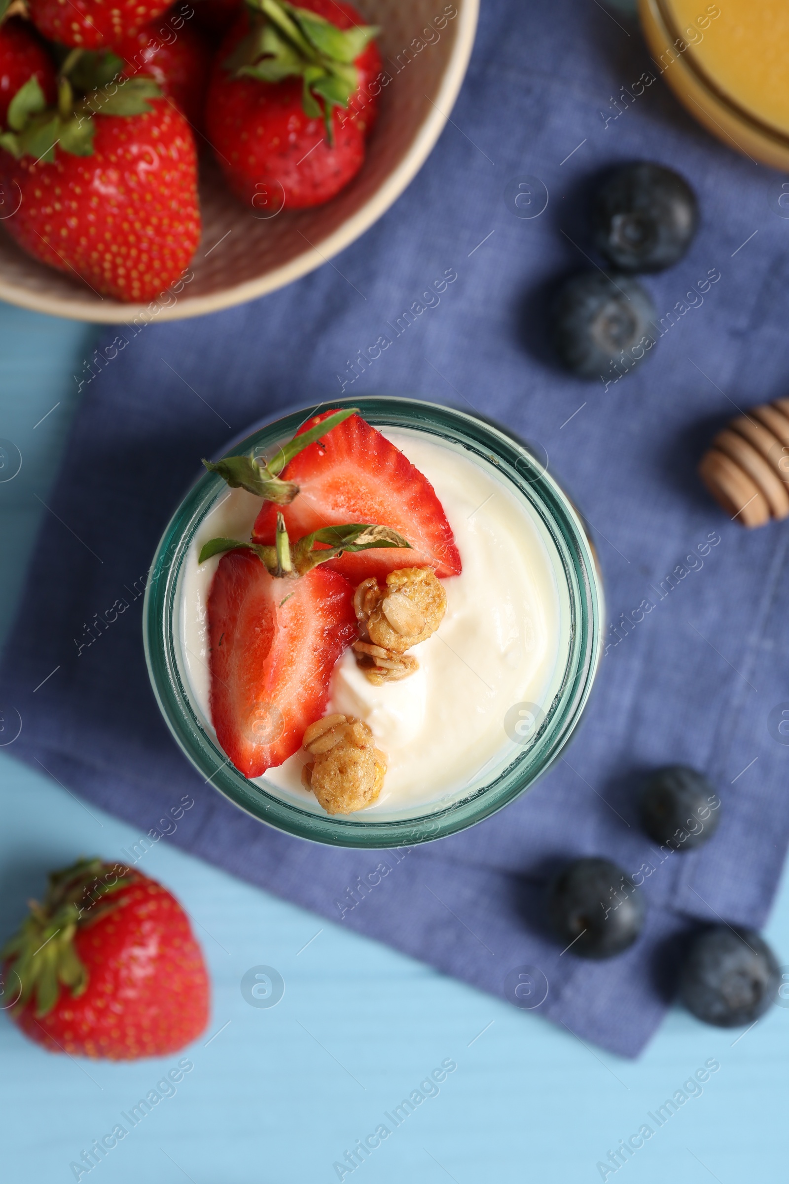 Tasty yogurt with granola and berries on light blue wooden table, flat lay Photo of Tasty yogurt with granola and berries on light blue wooden table, flat lay
