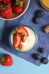 Photo of Tasty yogurt with granola and berries on light blue wooden table, flat lay