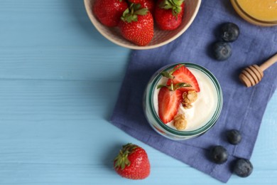 Photo of Tasty yogurt with granola and berries on light blue wooden table, flat lay. Space for text