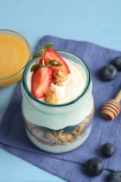 Photo of Tasty yogurt with granola, berries and honey on light blue table, above view