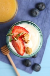 Photo of Tasty yogurt with granola, berries and honey on light blue table, flat lay