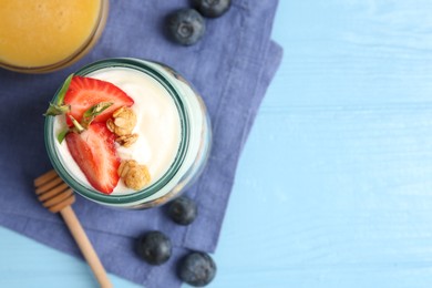 Photo of Tasty yogurt with granola, berries and honey on light blue wooden table, flat lay. Space for text