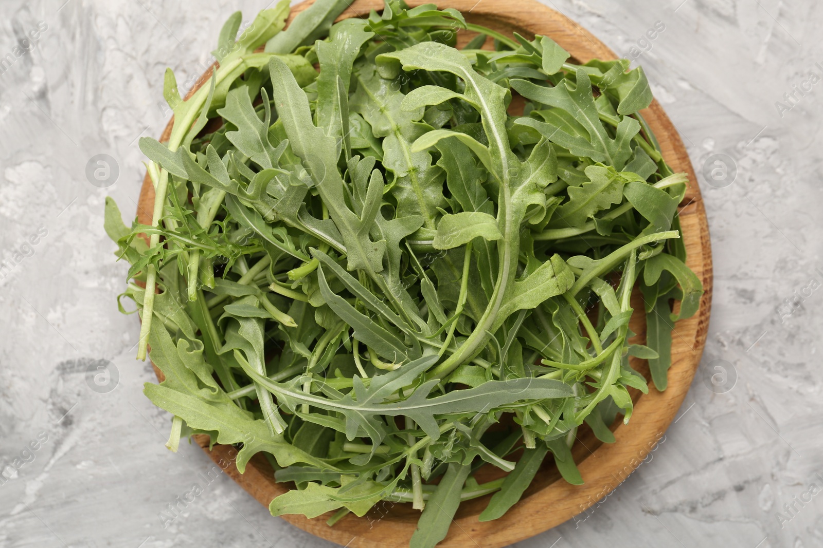 Fresh ripe green arugula leaves on grey table, top view Photo of Fresh ripe green arugula leaves on grey table, top view