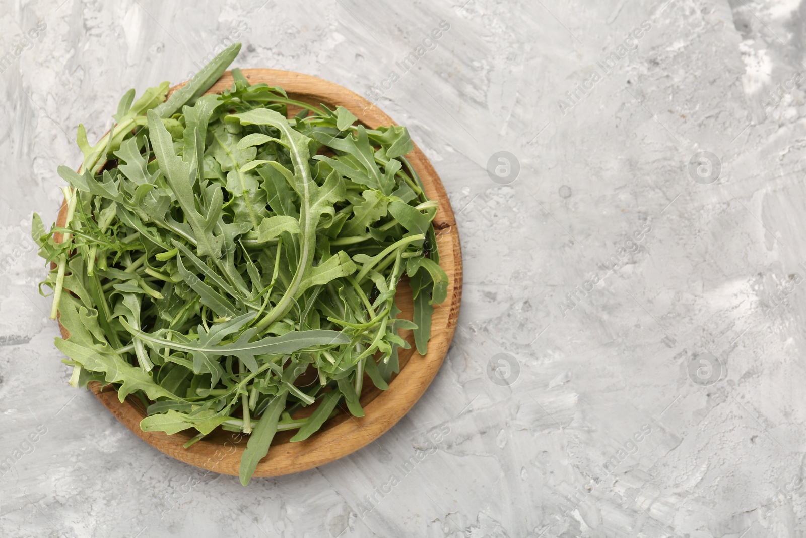 Fresh ripe green arugula leaves on grey table, top view. Space for text Photo of Fresh ripe green arugula leaves on grey table, top view. Space for text