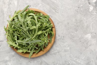 Photo of Fresh ripe green arugula leaves on grey table, top view. Space for text