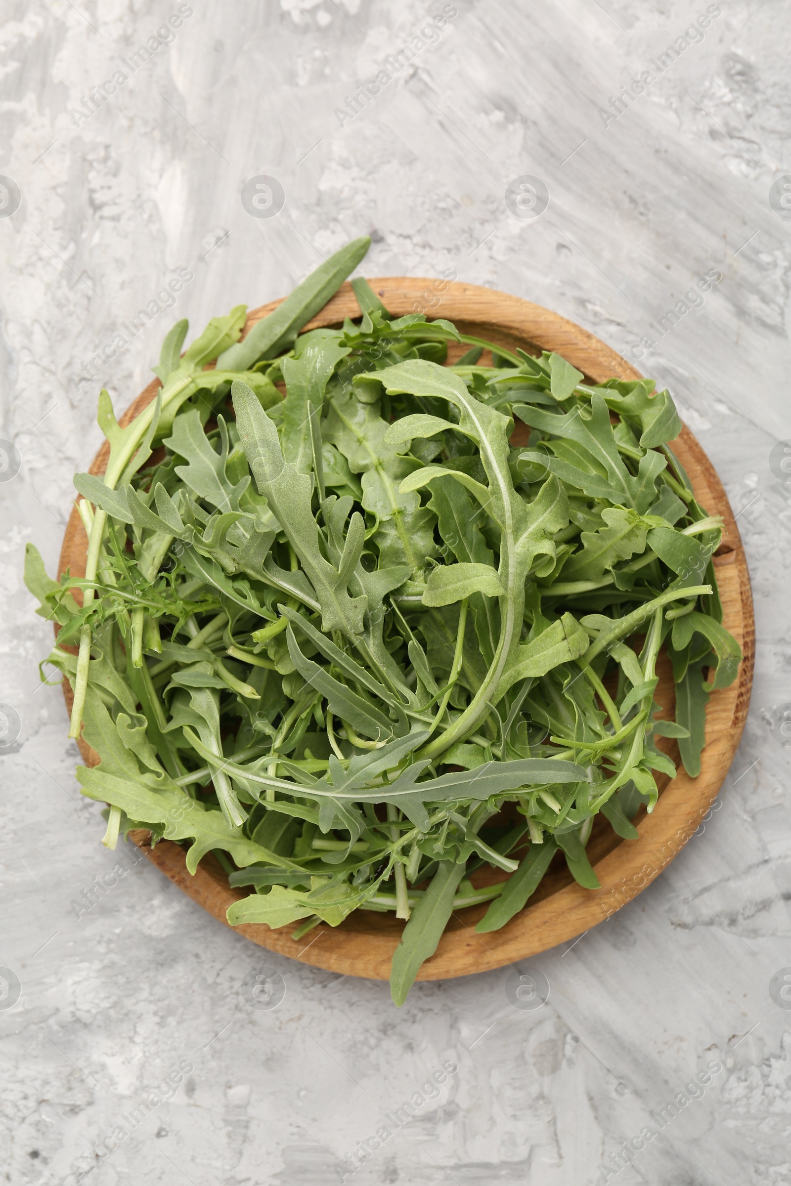 Fresh ripe green arugula leaves on grey table, top view Photo of Fresh ripe green arugula leaves on grey table, top view