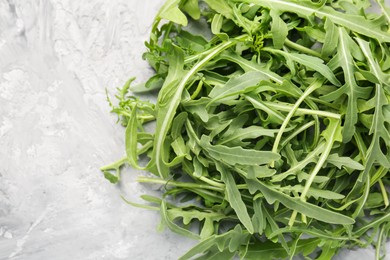 Photo of Fresh ripe green arugula leaves on grey table, top view. Space for text
