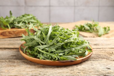 Photo of Fresh ripe green arugula leaves on wooden table, closeup