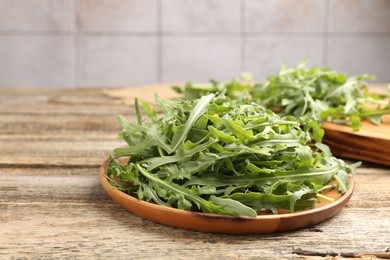 Photo of Fresh ripe green arugula leaves on wooden table, closeup. Space for text