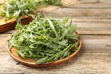 Photo of Fresh ripe green arugula leaves on wooden table, closeup. Space for text