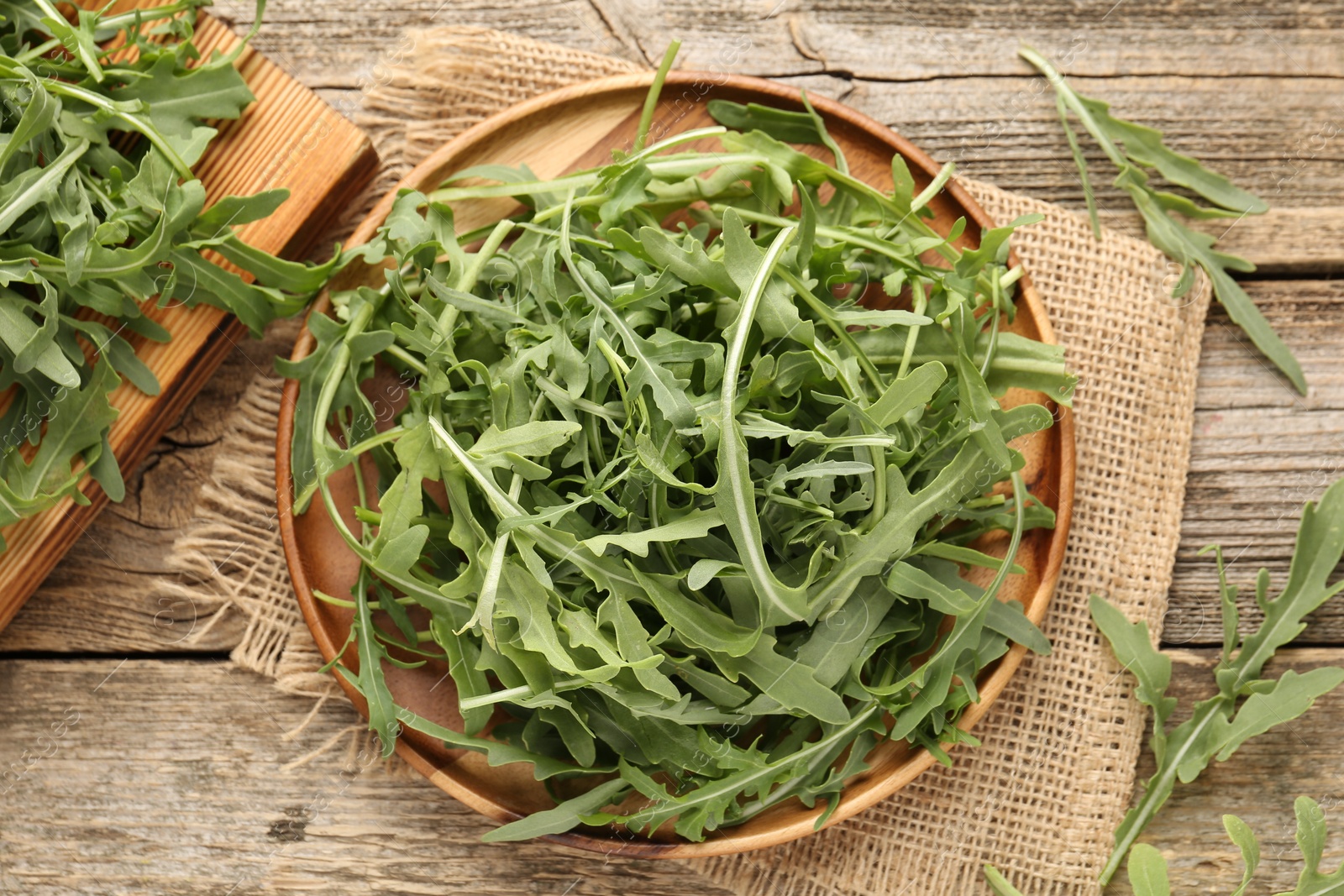 Fresh ripe green arugula leaves on wooden table, flat lay Photo of Fresh ripe green arugula leaves on wooden table, flat lay