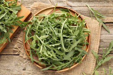Photo of Fresh ripe green arugula leaves on wooden table, flat lay