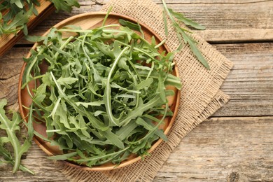 Photo of Fresh ripe green arugula leaves on wooden table, flat lay. Space for text