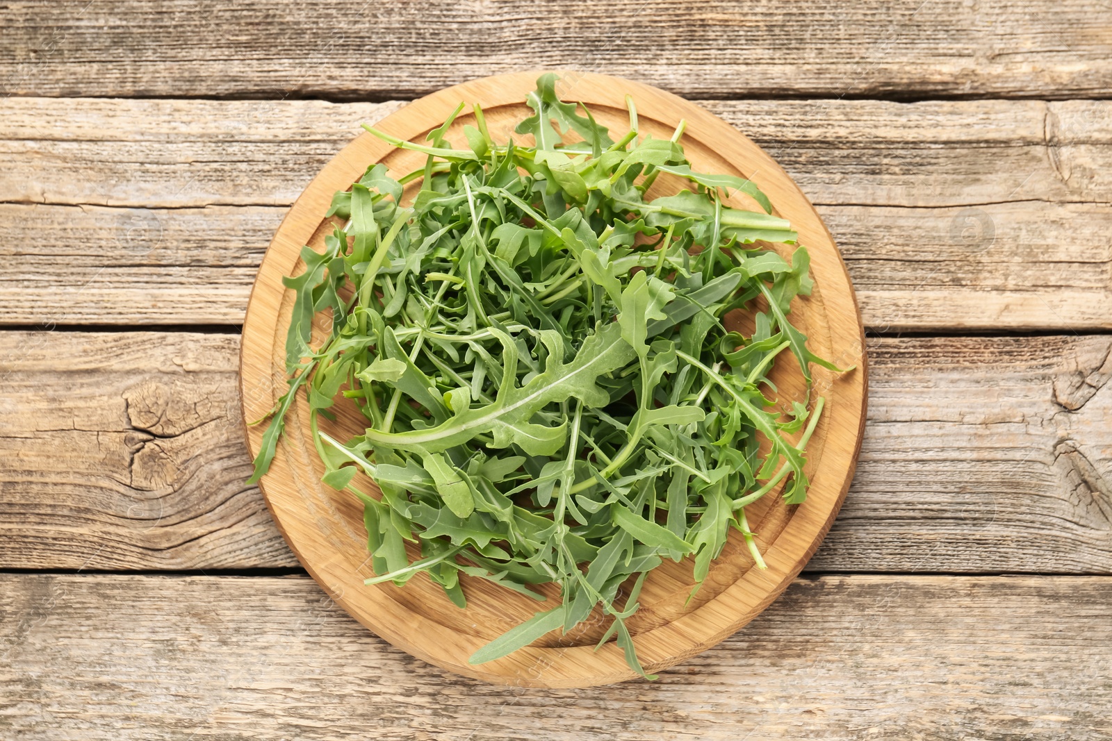Fresh ripe green arugula leaves on wooden table, top view Photo of Fresh ripe green arugula leaves on wooden table, top view