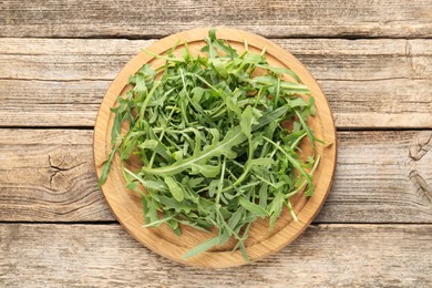Photo of Fresh ripe green arugula leaves on wooden table, top view