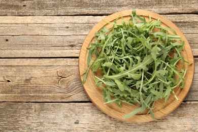 Photo of Fresh ripe green arugula leaves on wooden table, top view. Space for text