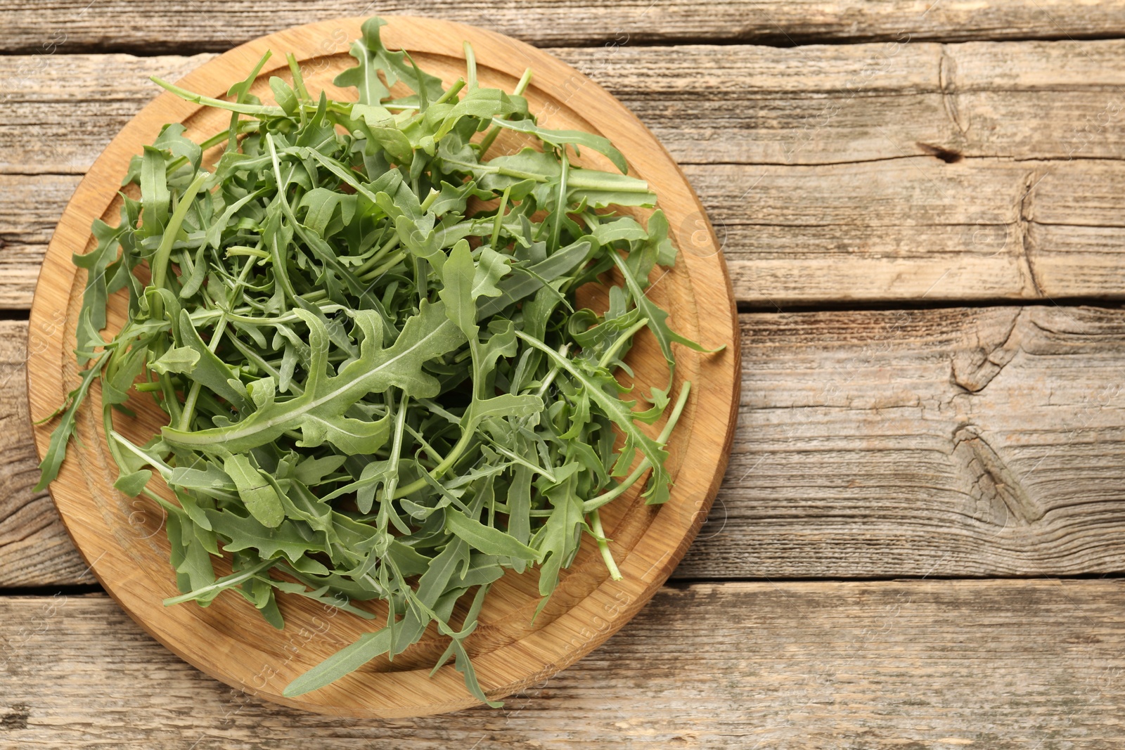 Fresh ripe green arugula leaves on wooden table, top view. Space for text Photo of Fresh ripe green arugula leaves on wooden table, top view. Space for text