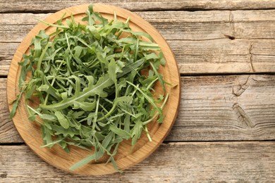 Photo of Fresh ripe green arugula leaves on wooden table, top view. Space for text