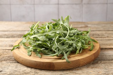 Photo of Fresh ripe green arugula leaves on wooden table, closeup