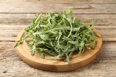 Photo of Fresh ripe green arugula leaves on wooden table, closeup